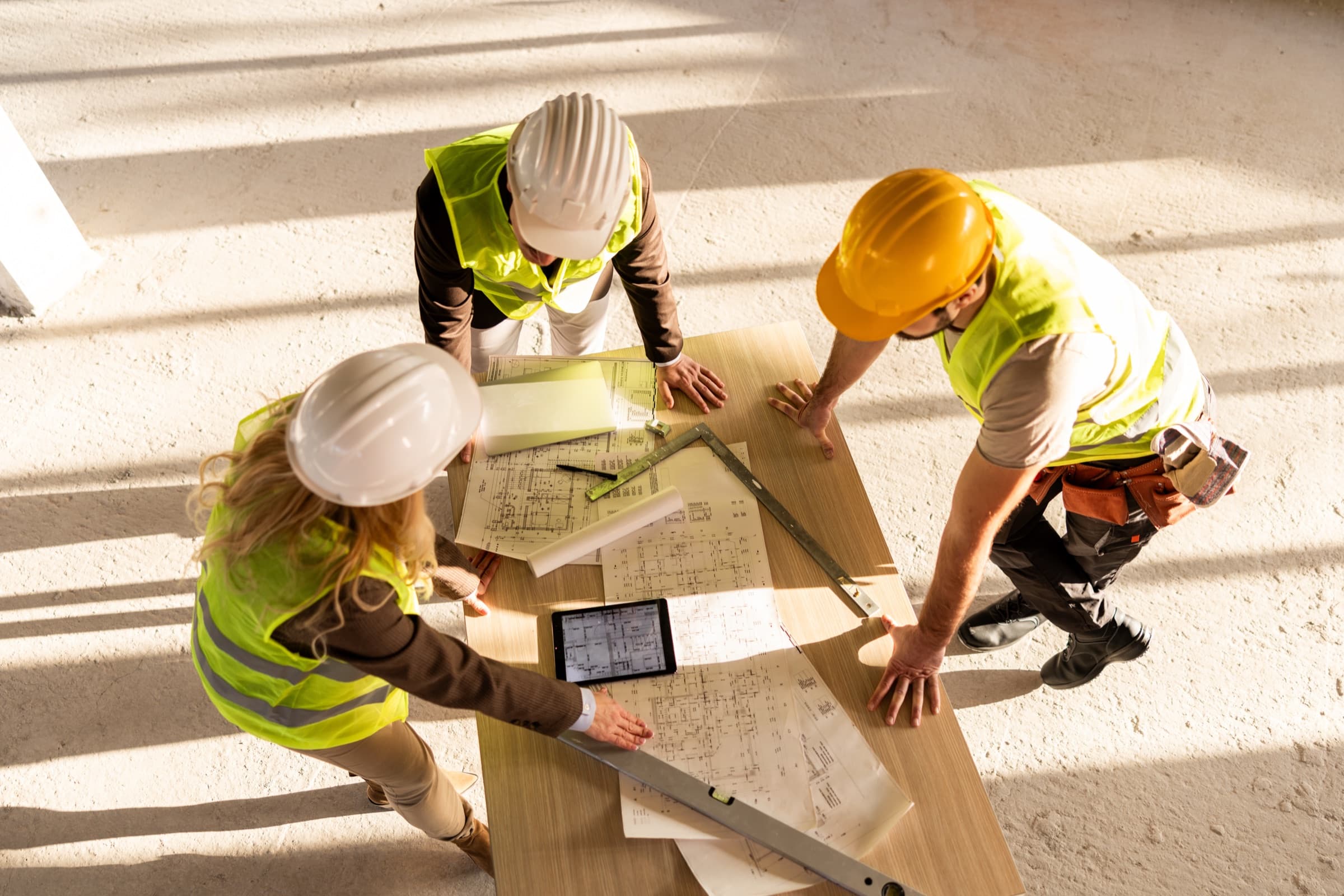Three people in hi-vis reviewing plans on a job site